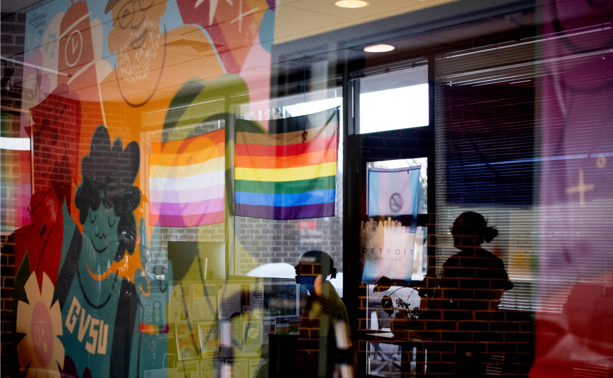 D. Hollowell, assistant director of the Milton E. Ford LGBT Resource Center, center, smiles while watching a new mural being installed in the room. Hollowell described the mural by artist Rhiannan Sibbald as “lively.” “It emanates the kind of ene...